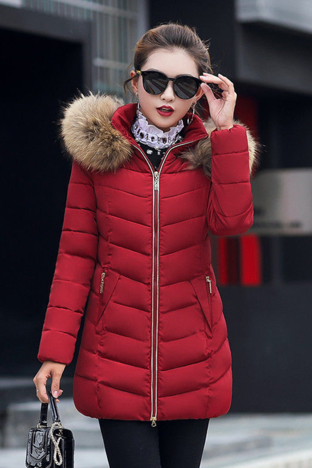 Woman wearing a red puffer jacket with fur hood in an urban setting