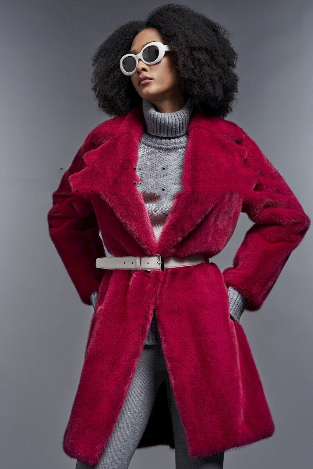 Person wearing a red coat and gray sweater against a gray background