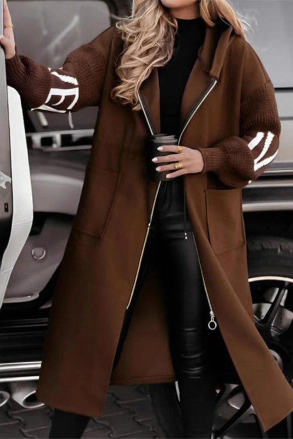 Person wearing a brown coat with white accents, standing next to a car.
