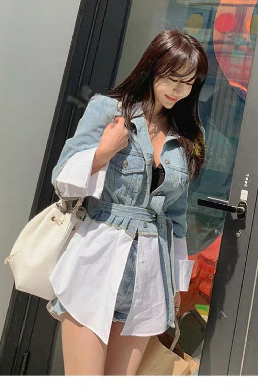 Woman in a denim outfit standing in front of a colorful door.