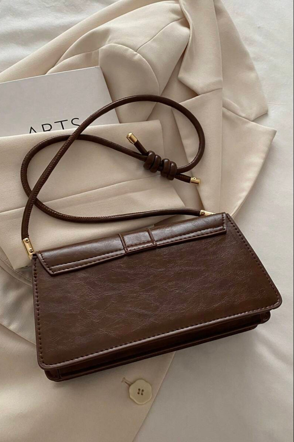 Brown leather handbag on a beige fabric background