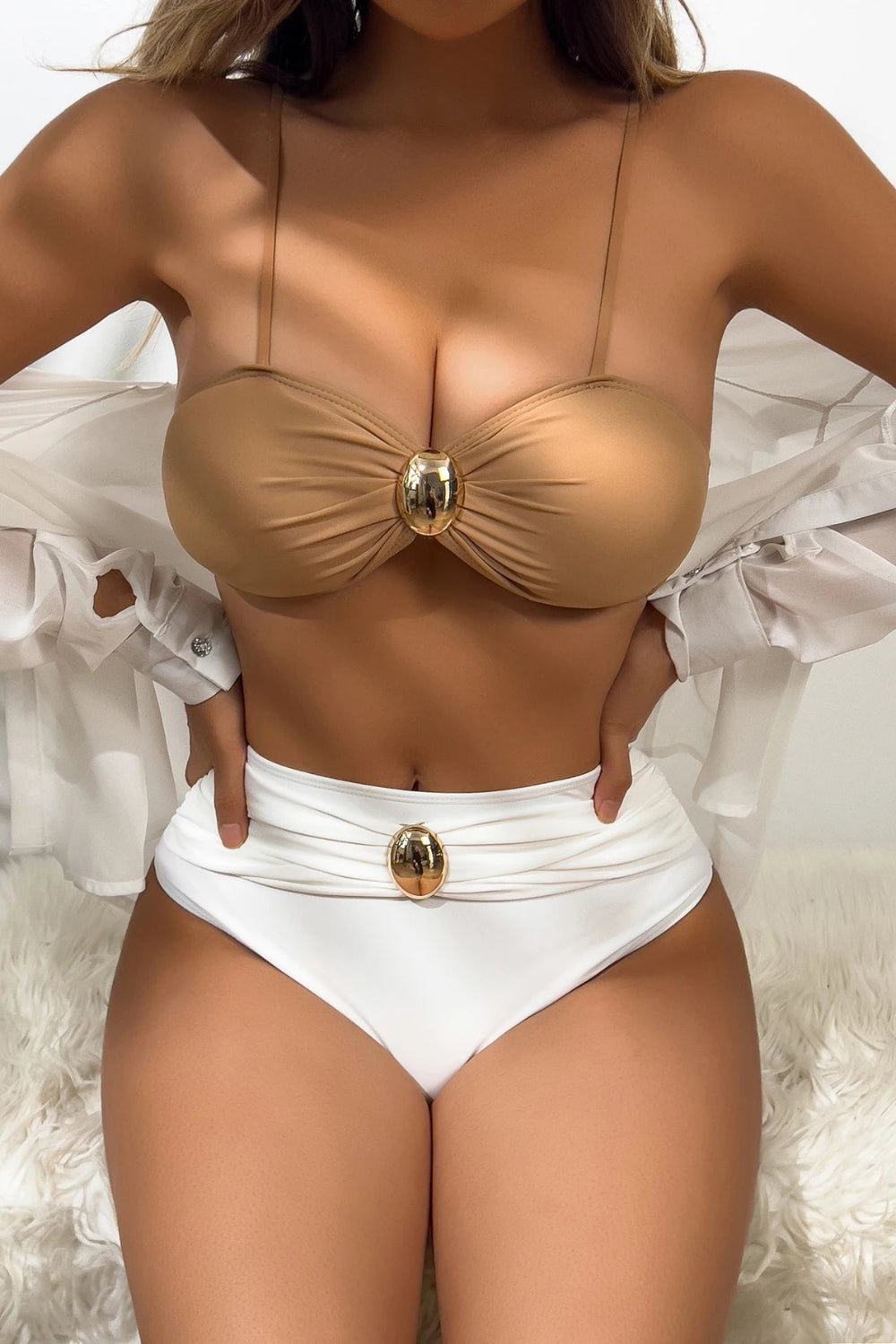 Person wearing a beige bikini top and white high-waisted bottoms with gold buttons on a white background