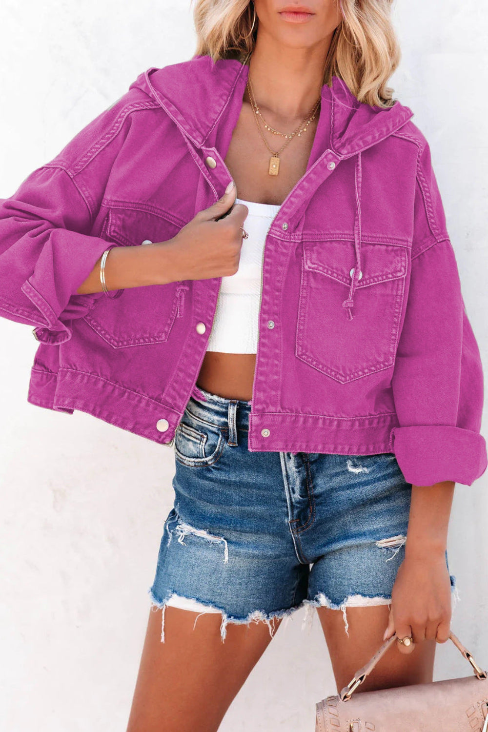 Person wearing a bright purple denim jacket and denim shorts on a white background