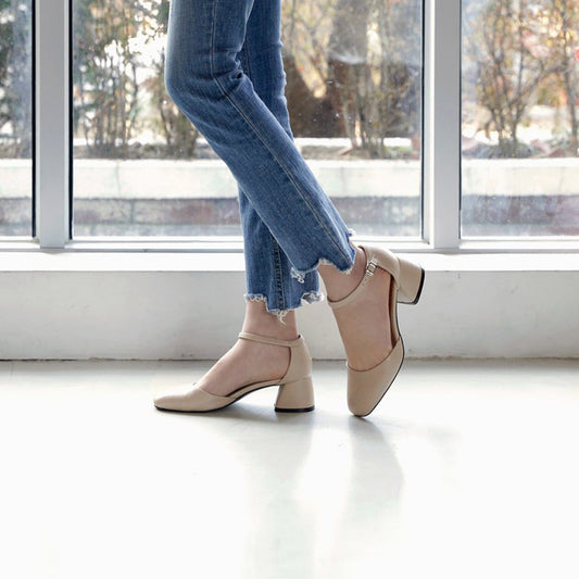 Person wearing beige shoes and blue jeans standing in front of a window.
