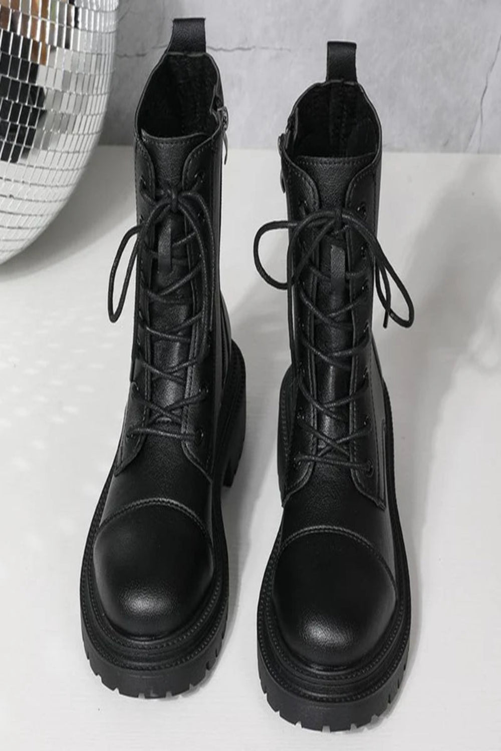 Pair of black lace-up boots on a light gray background