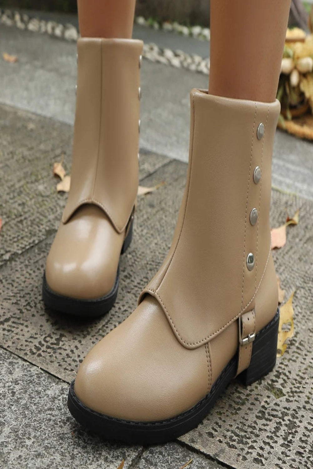 Beige ankle boots with button details on a textured pavement