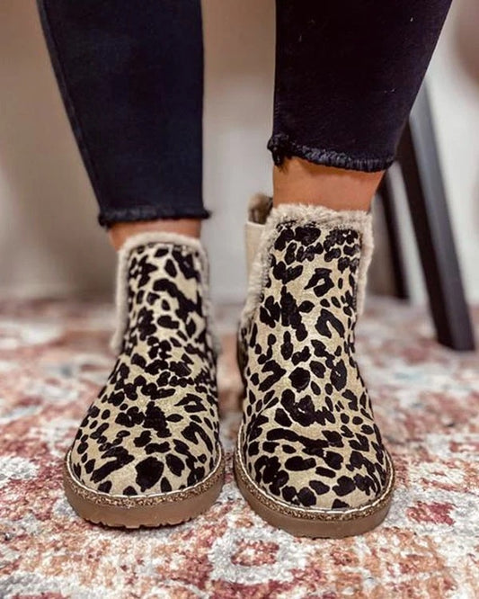 Leopard print boots worn with black pants on a patterned rug.