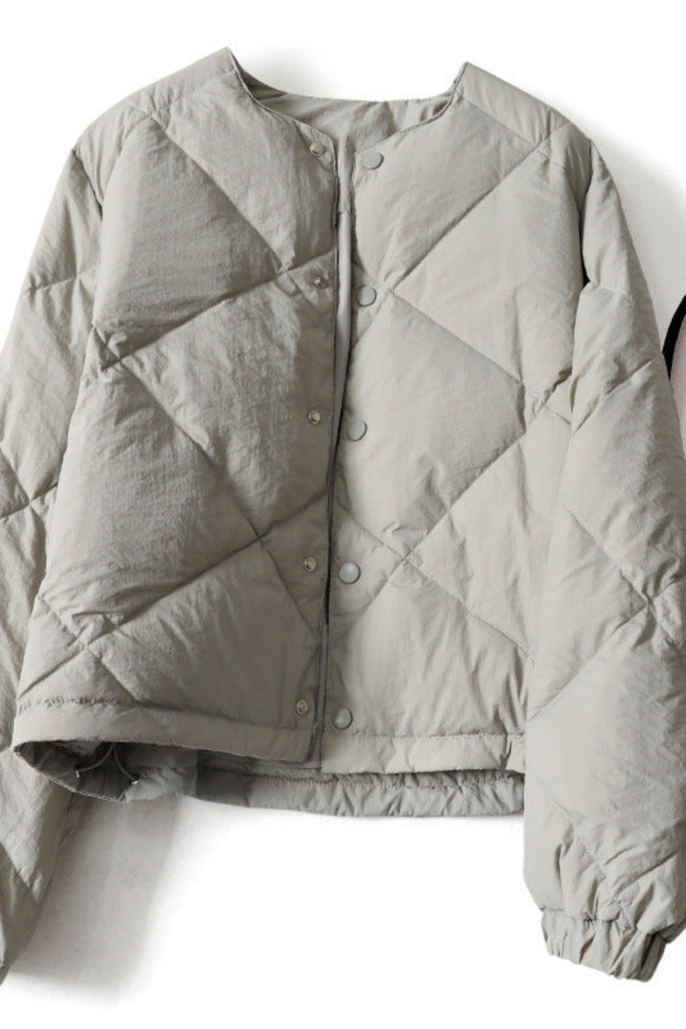 Gray quilted jacket on a white background with a black bag.
