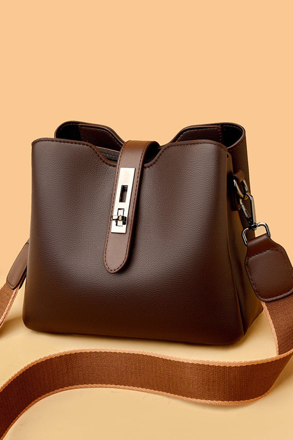 Brown leather handbag with a strap on a beige background