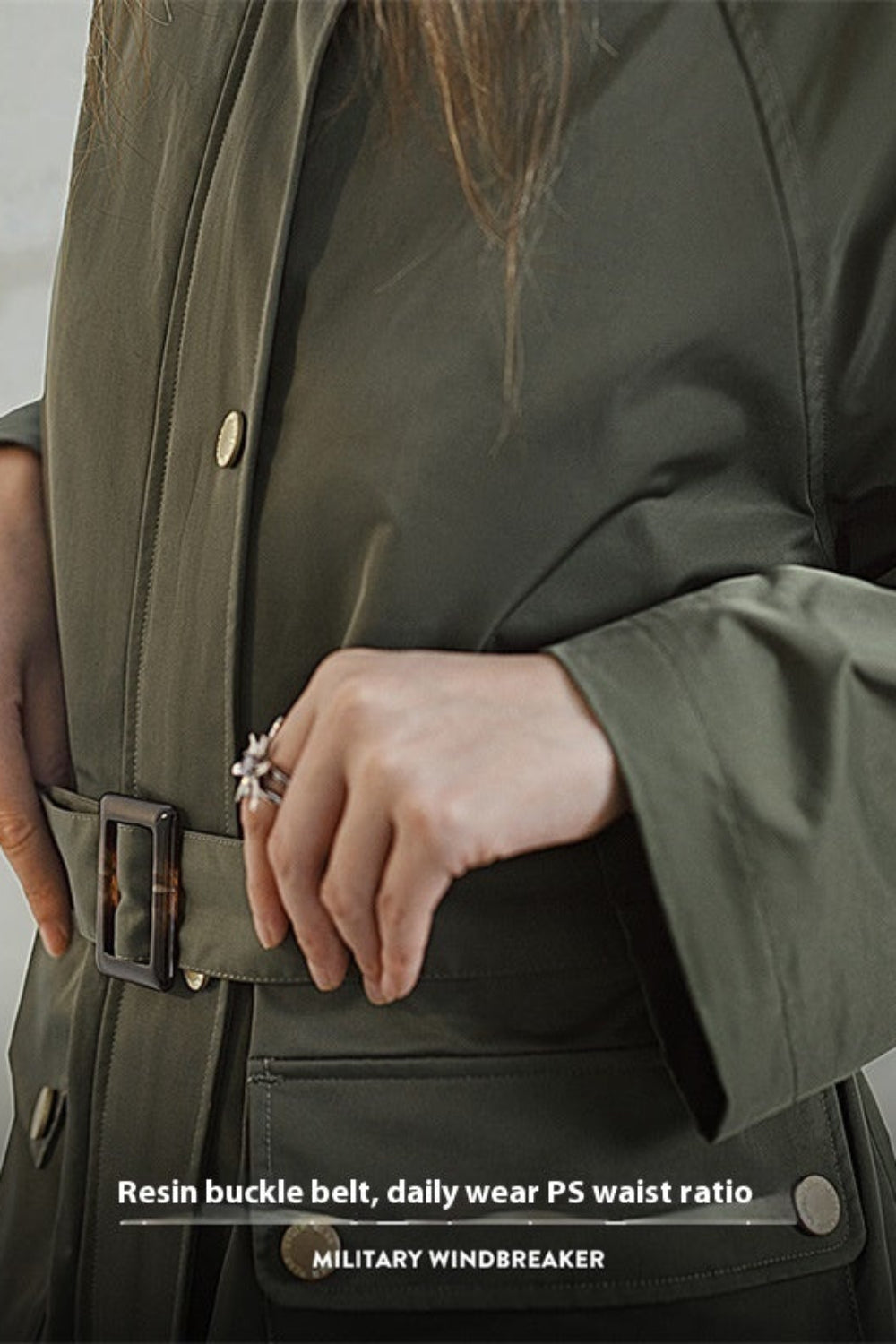 Person wearing a military-style windbreaker with a belt, on a neutral background