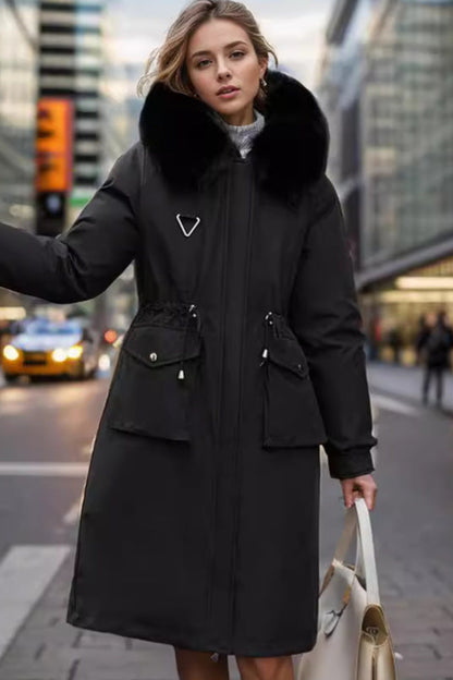 Woman in a black coat with fur hood standing on a city street.