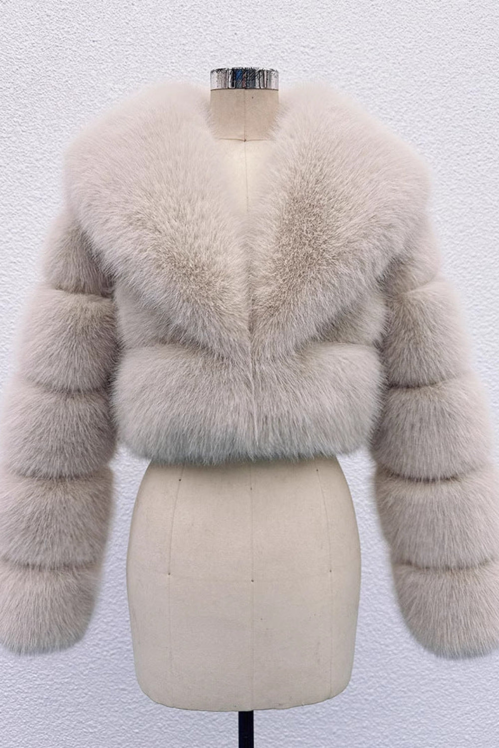 Beige fur jacket on a mannequin against a white background