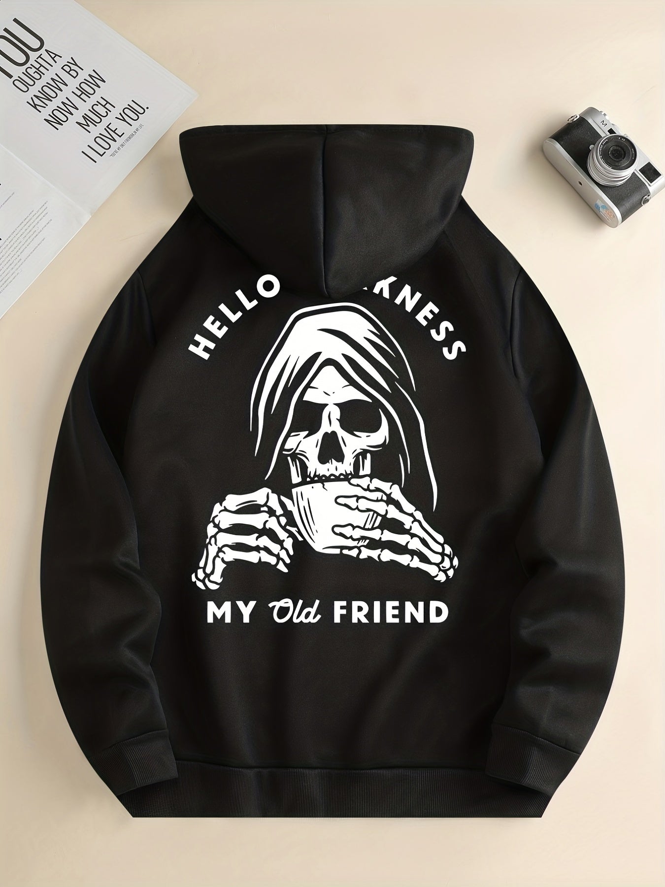 Black hoodie with a skull design and text on a beige background