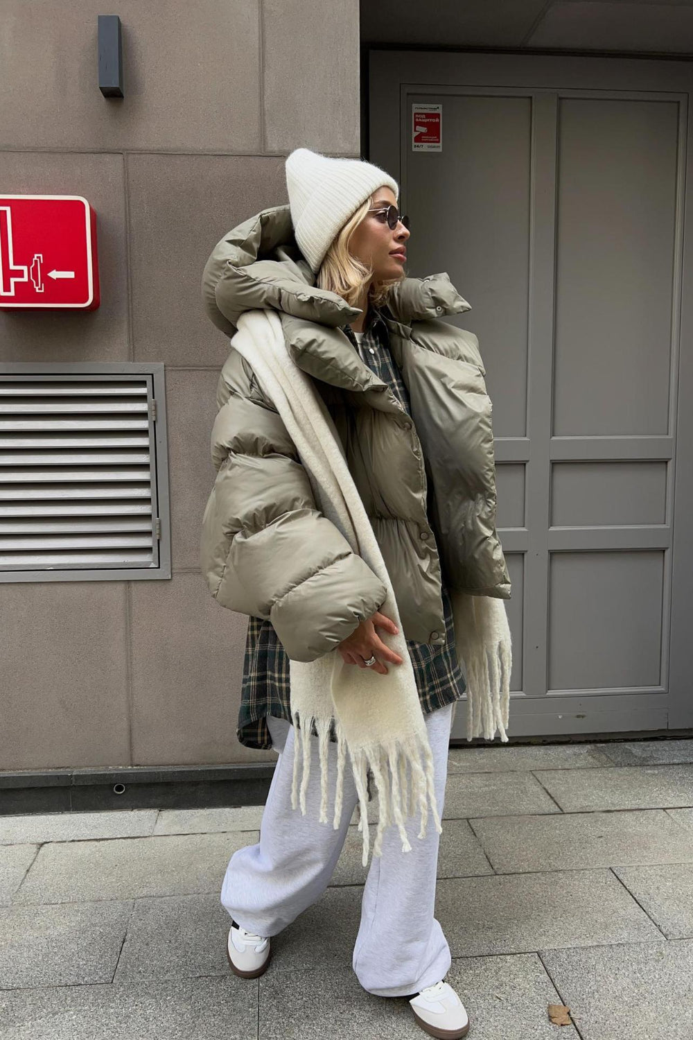 Person wearing a large beige puffer coat with a scarf in an urban setting