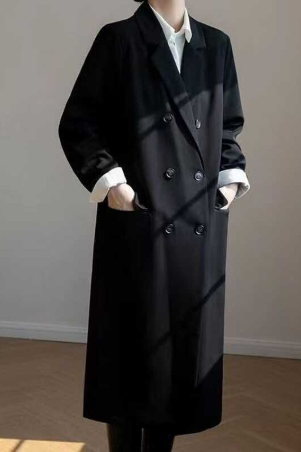 Black overcoat worn by a person against a plain background