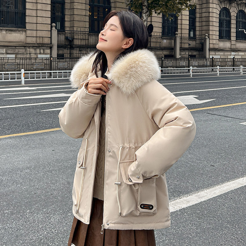 Woman wearing a beige parka with a fur-lined hood in an urban setting