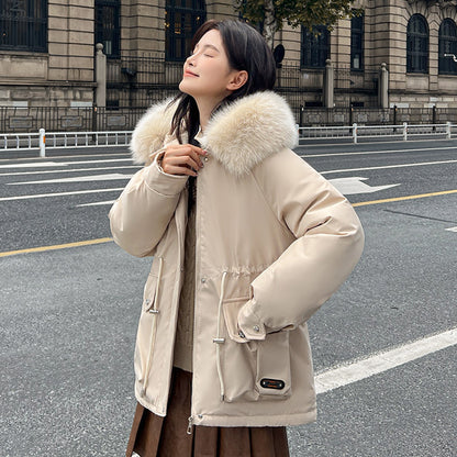 Woman wearing a beige parka with a fur-lined hood in an urban setting