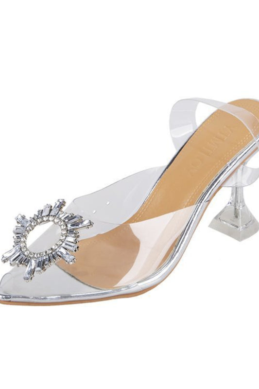 Silver high-heeled shoe with a clear heel and decorative embellishment on a white background