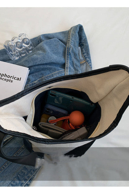 Open bag with denim jacket, book, and various items on a light gray background