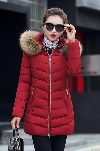 Woman wearing a red puffer jacket with fur hood in an urban setting