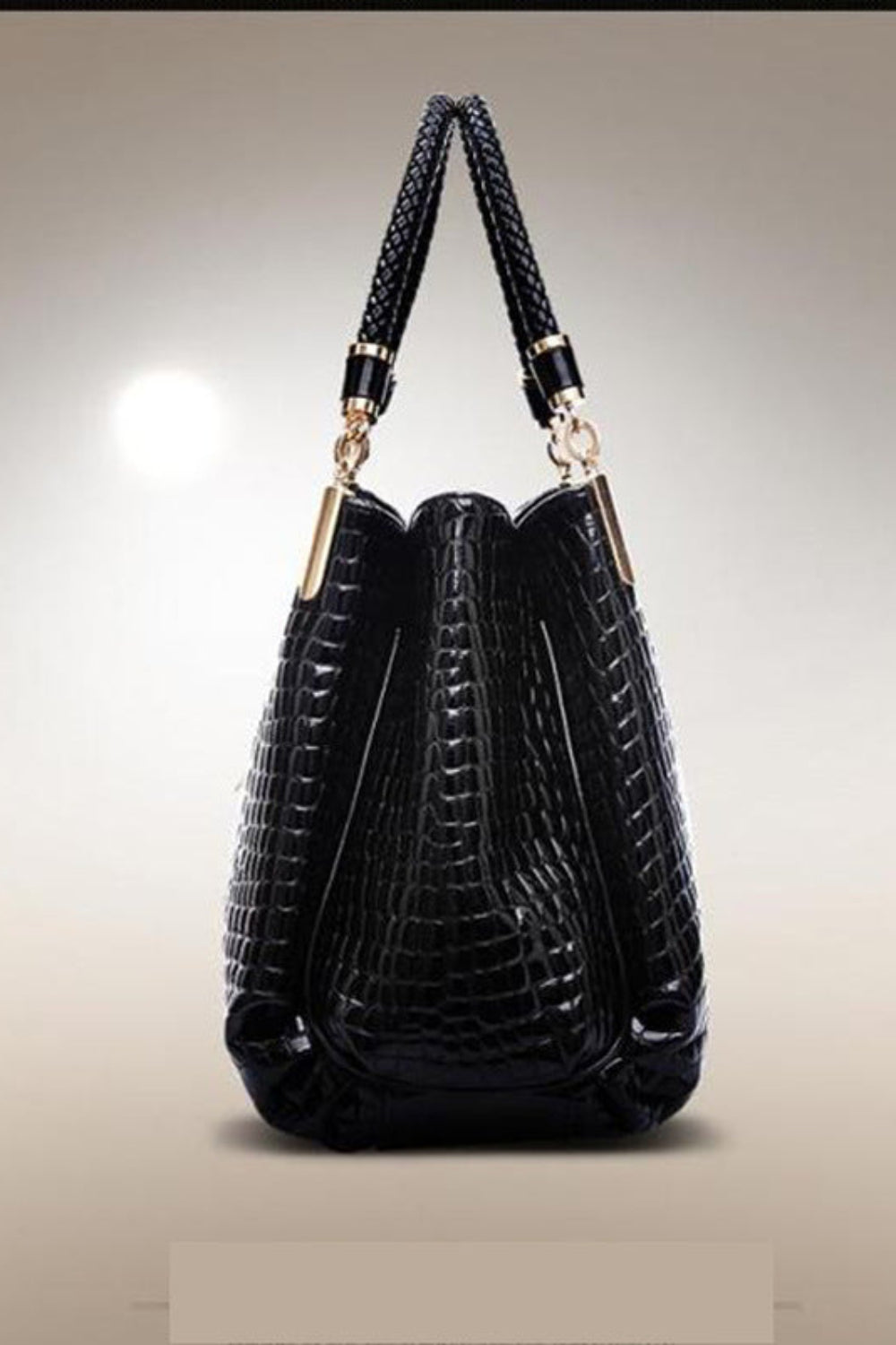 Black crocodile-patterned handbag with gold accents on a beige background
