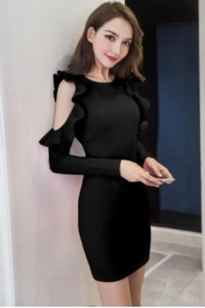 Woman wearing a black dress with ruffled sleeves in an indoor setting