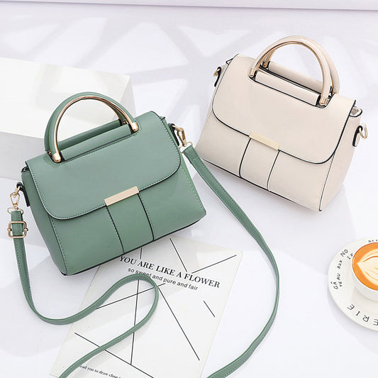 Two handbags, one green and one beige, on a white surface with a coffee cup in the background.