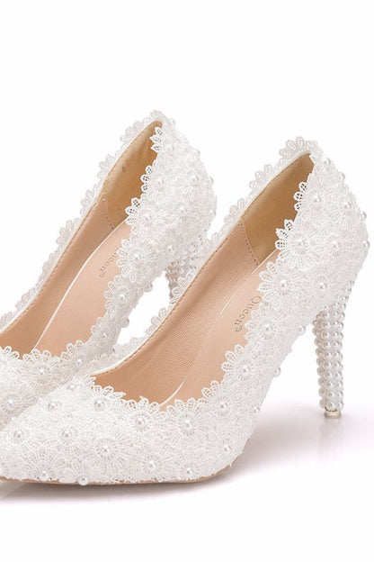 White high-heeled shoes with pearl detailing on a white background