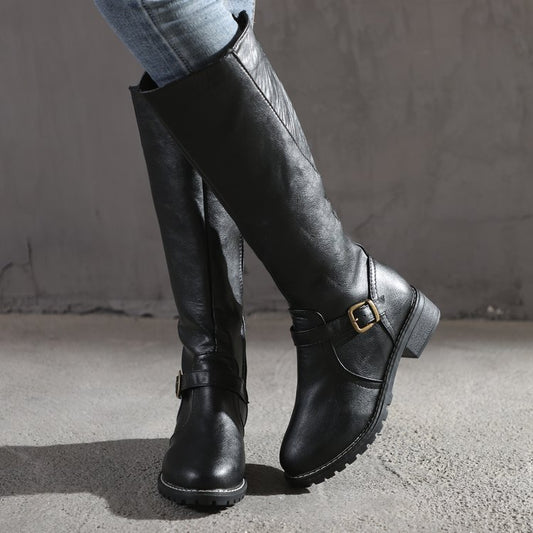 Black knee-high boots with a buckle on a neutral background