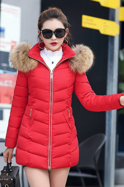 Woman wearing a red puffer coat with fur hood in an urban setting