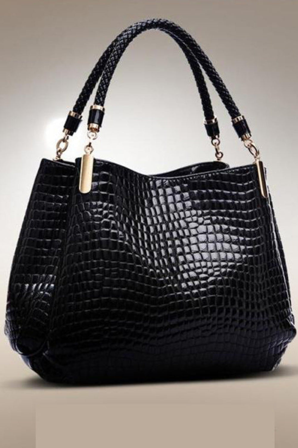 Black crocodile-patterned handbag with braided handles on a beige background