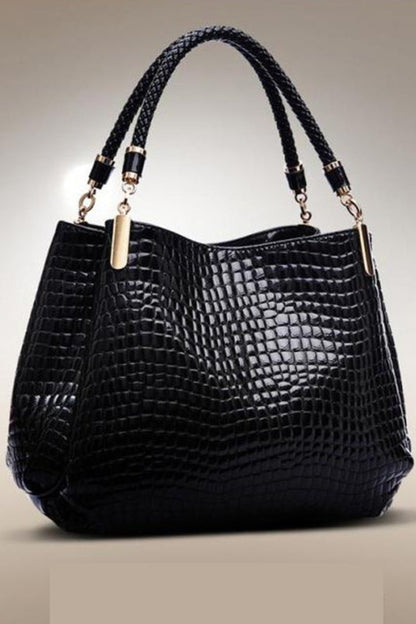 Black crocodile-patterned handbag with braided handles on a beige background