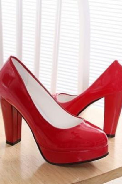 Red high-heeled shoes on a wooden surface with white blinds in the background