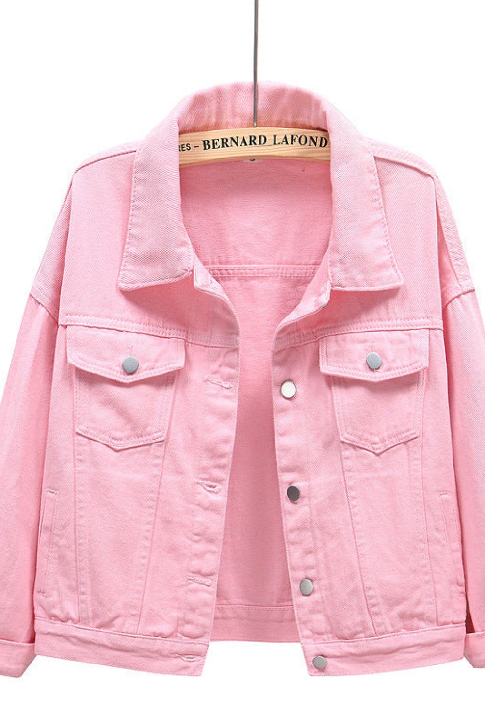Pink denim jacket on a hanger with a white background