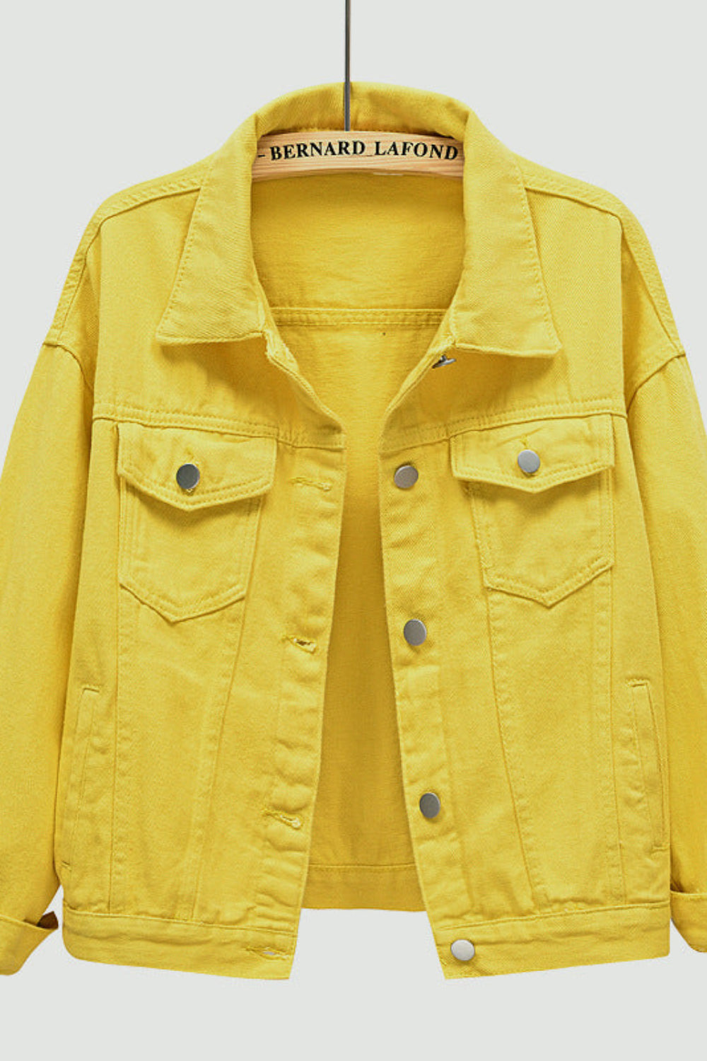 Yellow denim jacket on a hanger with a light gray background