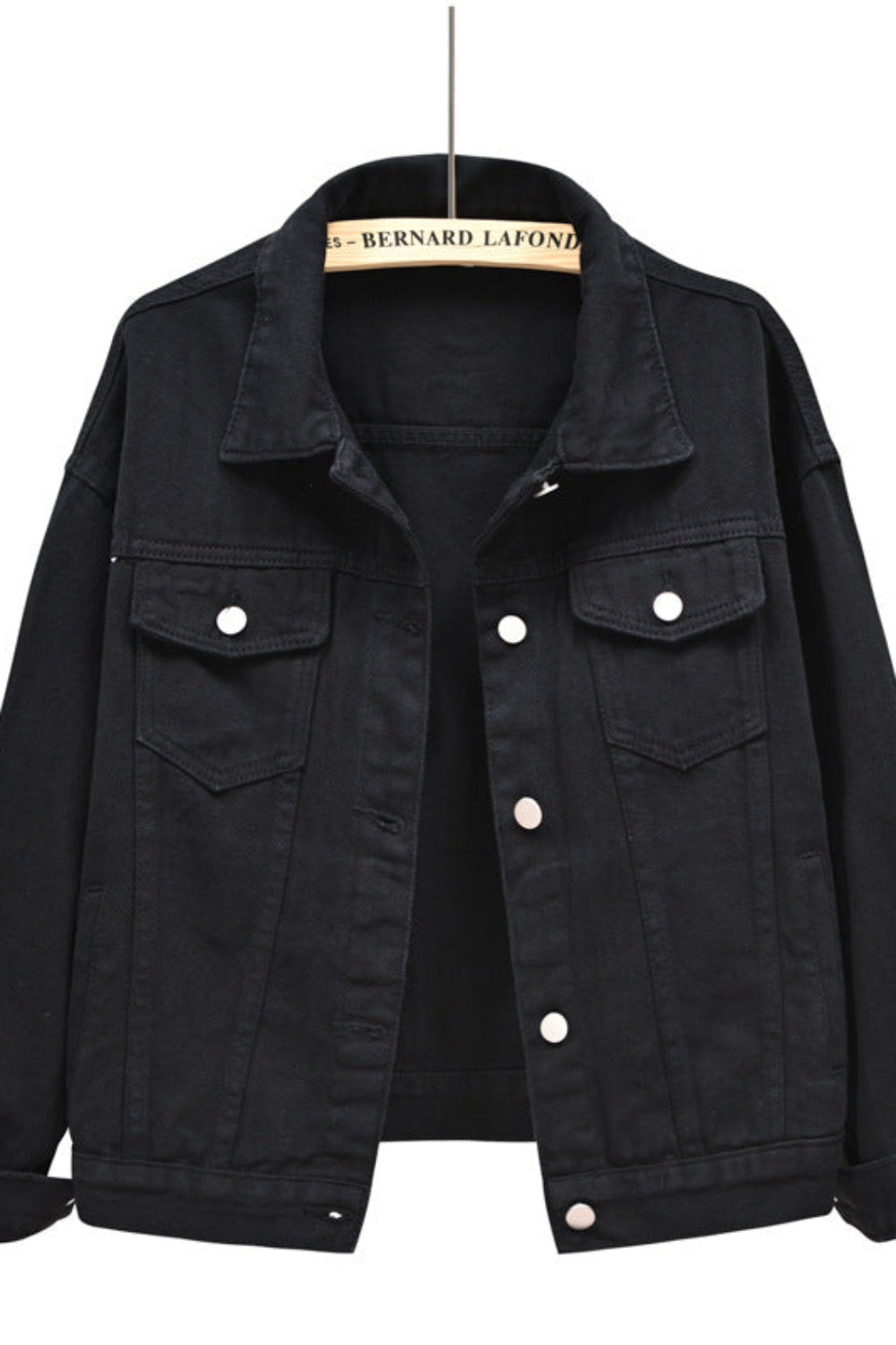 Black denim jacket on a hanger with a white background