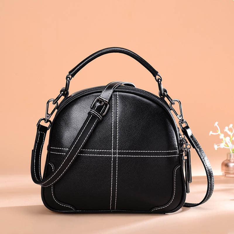 Black handbag with a strap on a beige background