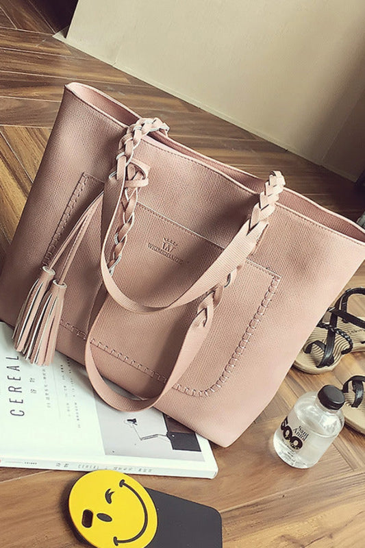 Pink handbag on a wooden floor with a book and water bottle nearby