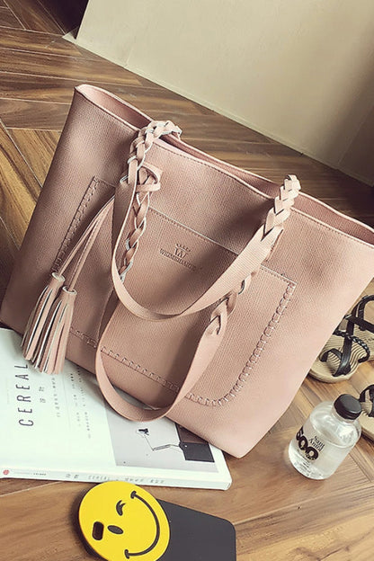 Pink handbag on a wooden floor with a book and water bottle nearby