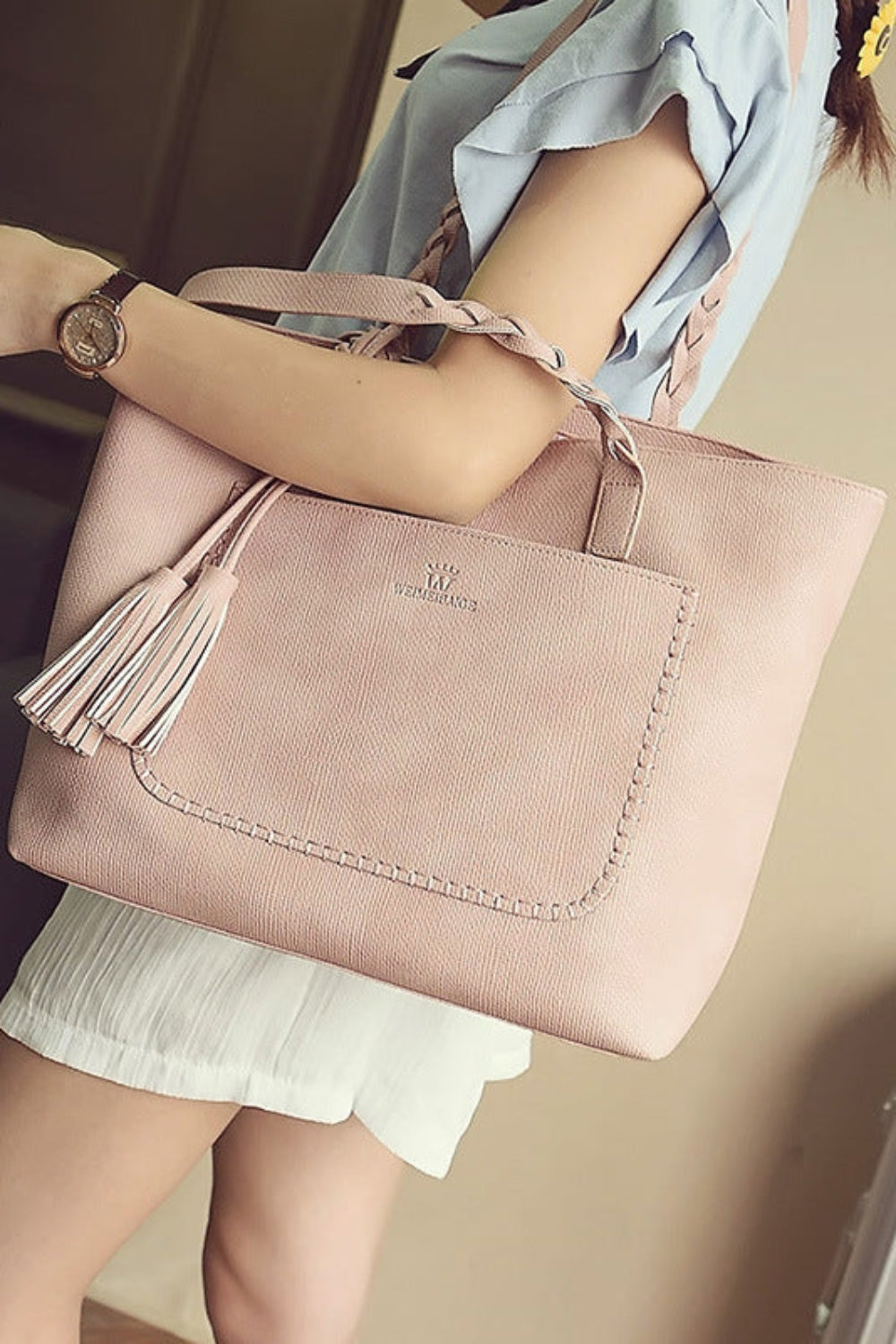 Person holding a pink handbag with a visible brand logo.