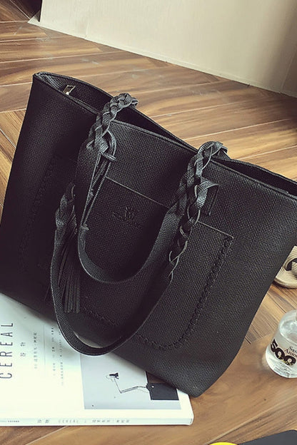 Black handbag on a wooden floor with a magazine and water bottle nearby