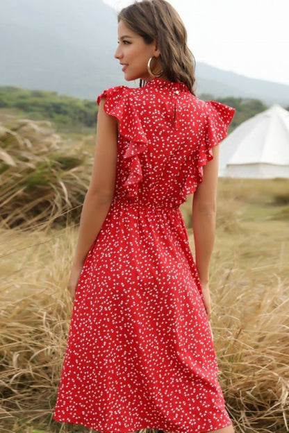 Woman in a red dress with white polka dots standing in a field with a tent in the background.