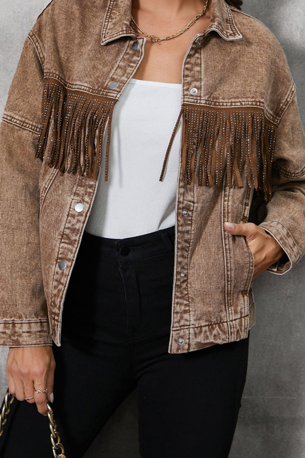 Person wearing a brown fringed jacket against a gray background