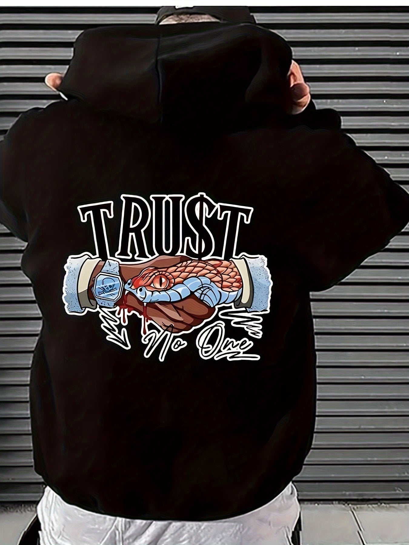 Person wearing a black hoodie with a graphic design on the back, featuring text and imagery.