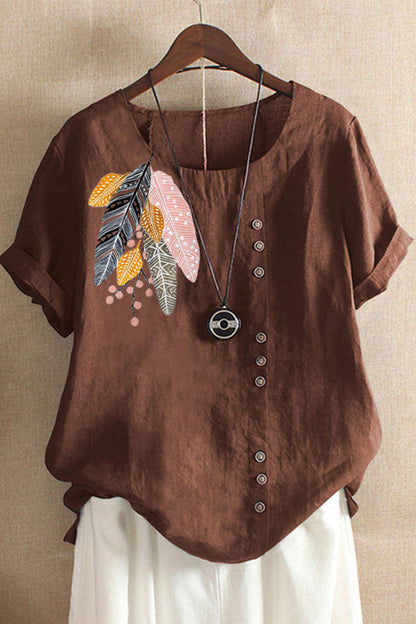 Brown shirt with feather design on a hanger against a beige wall