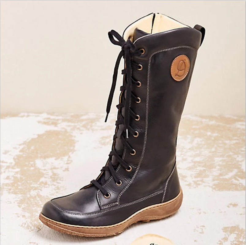 Black leather boot with brown sole on a textured beige background