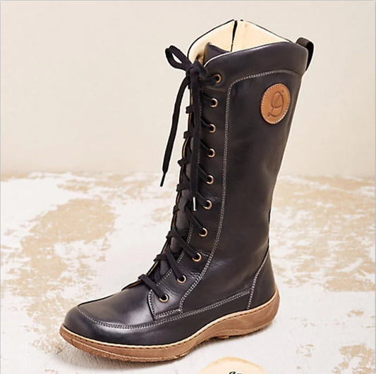 Black leather boot with brown sole on a textured beige background