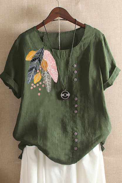 Green blouse with floral embroidery on a wooden hanger against a beige wall.