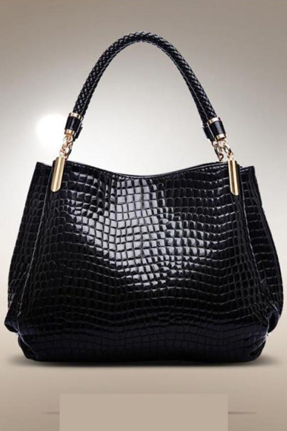 Black textured handbag with braided handle on a beige background