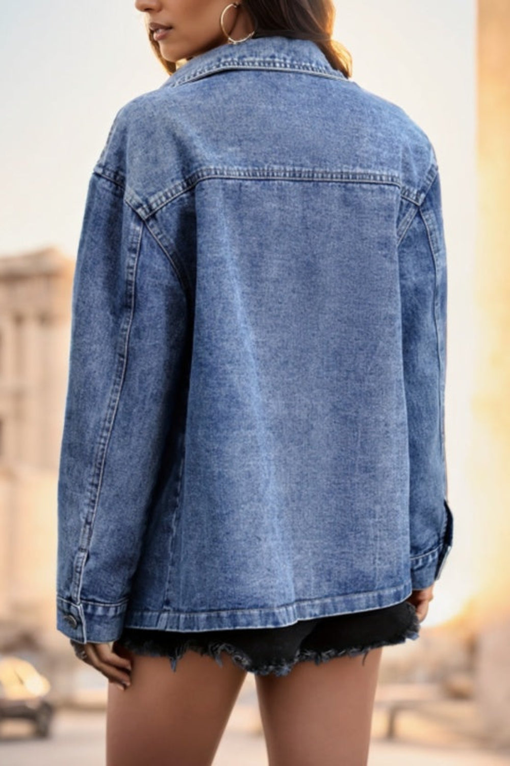 Person wearing a blue denim jacket outdoors with a blurred background